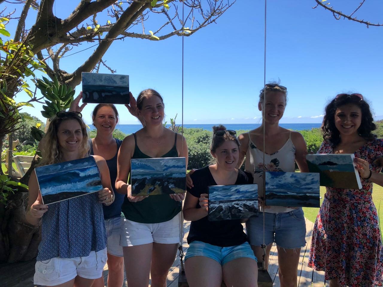 Guests showing their paintings after a workshop on the deck